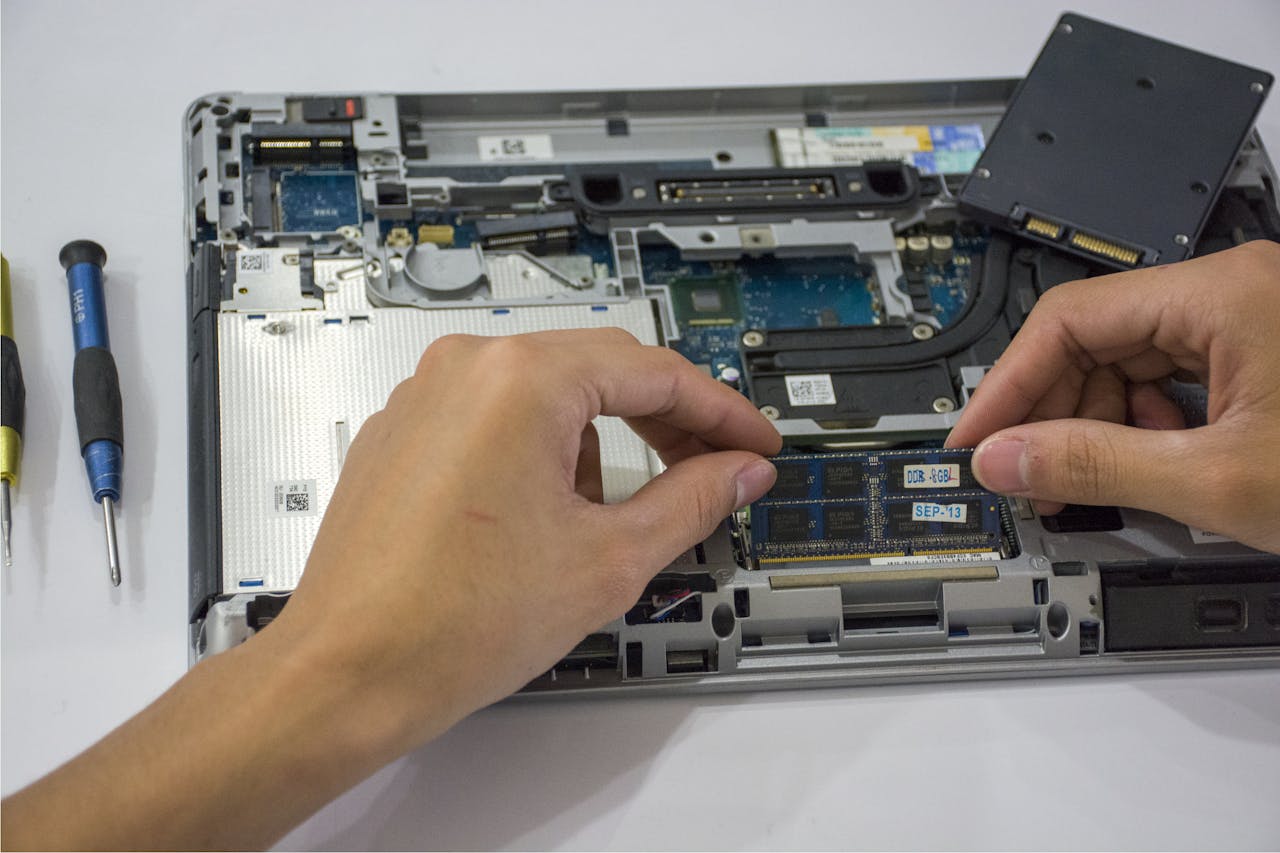 Services Close-up of a technician assembling a laptop's internal components using tools.