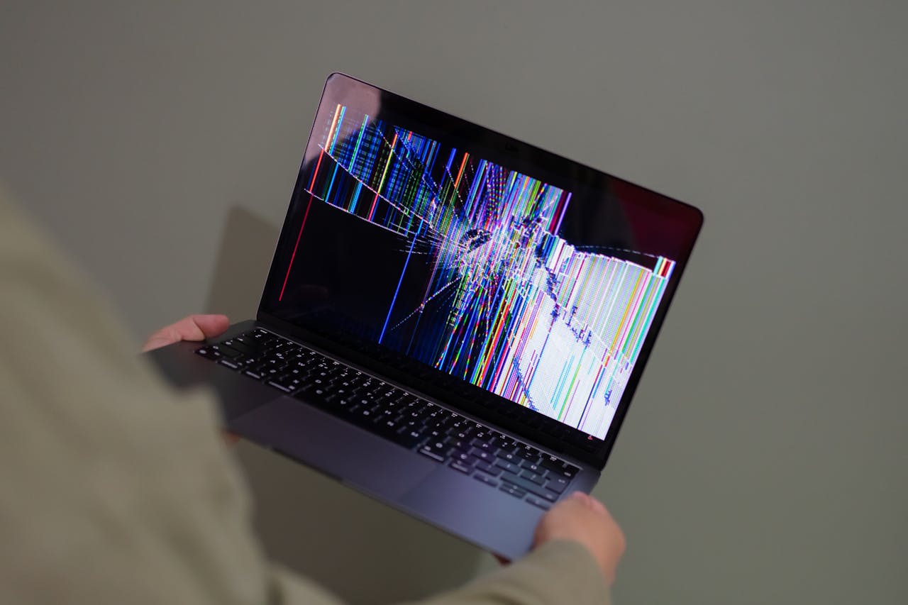 Mastering the First Impression: Your intriguing post title goes here A broken laptop screen displayed with colorful glitch being held by a person.