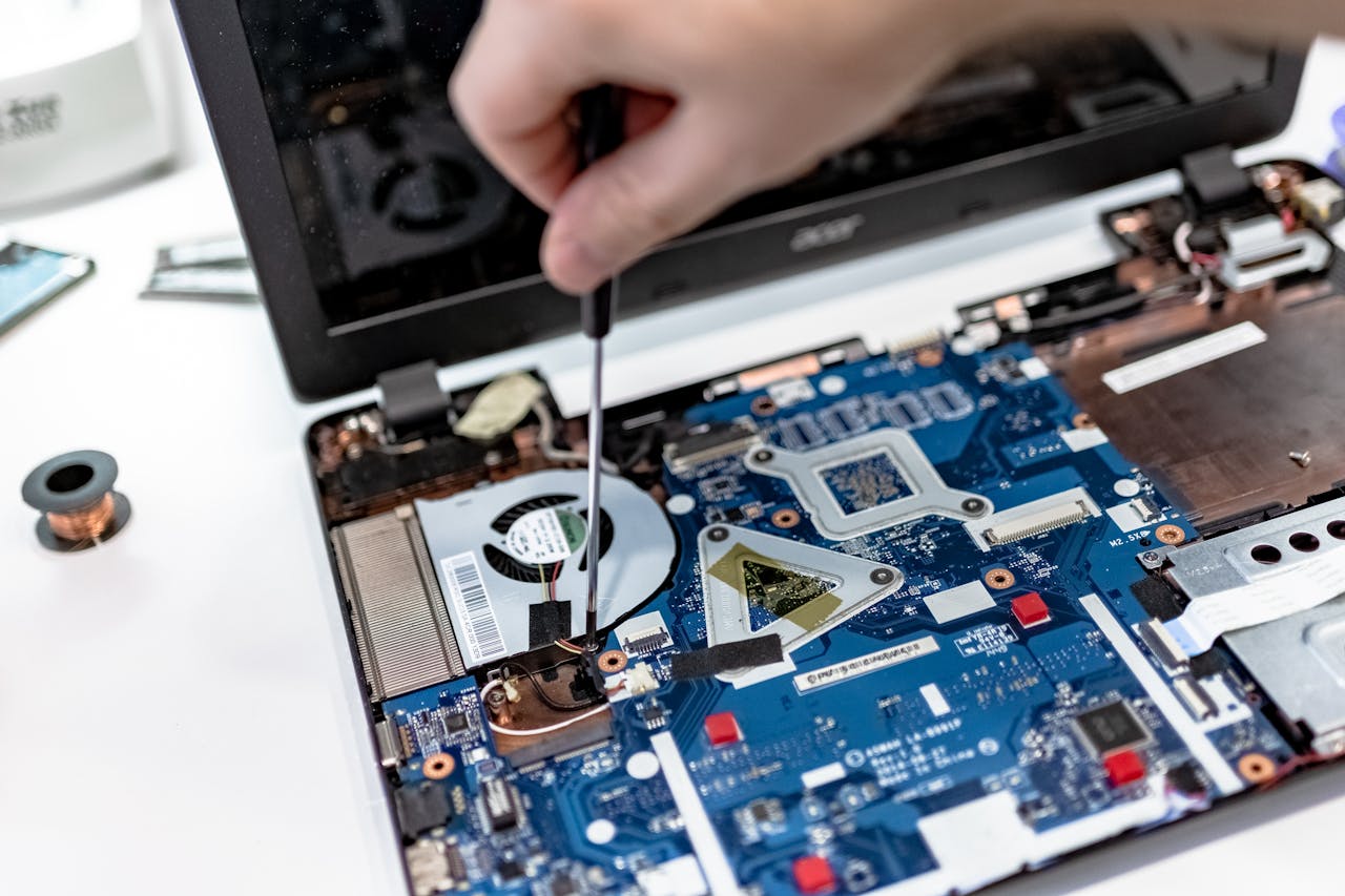 Crafting Captivating Headlines: Your awesome post title goes here Hand repairing a laptop motherboard with a screwdriver, highlighting tech maintenance.